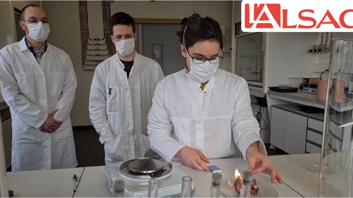 Photo de trois doctorants dans un laboratoire en train de faire brûler un matériau