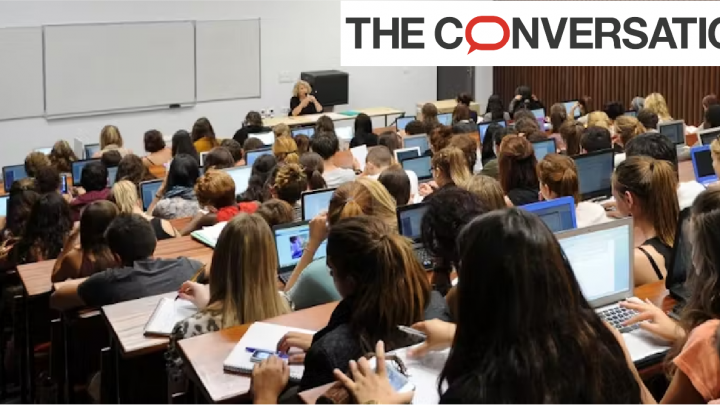 Dans un cours de langue vivante à l'université, les étudiants sont plusieurs dizaines dans un amphithéâtre face à leur enseignante.