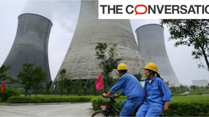 Deux ouvriers passant à vélo devant des cheminées de centrale nucléaire