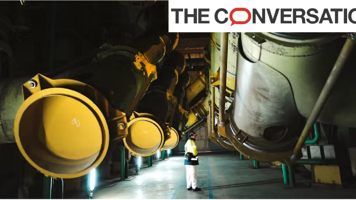 Homme debout au centre d'énormes tuyaux de central nucléaire